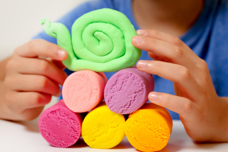 Child hands making toy figure with modeling clay or plasticineの写真素材