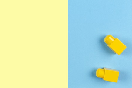 Two yellow plastic construction blocks on yellow and blue backgroundの写真素材