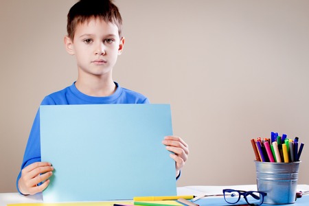 Child making greeting card. Boy holding sheet of colored paperの写真素材