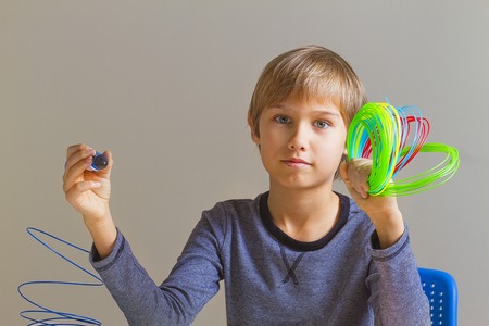 Boy holding 3 d pen and colorful filaments