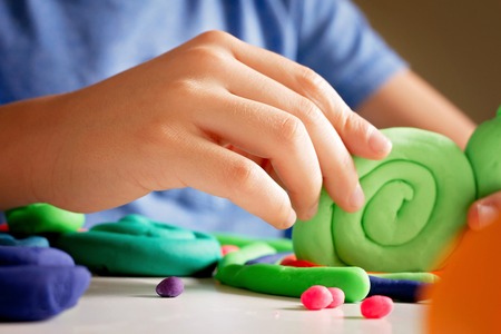 Child hands making toy figure with modeling clay or plasticineの写真素材