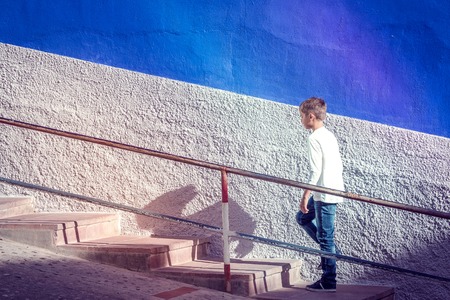 Young caucasian boy walking up stairs outdoors.の写真素材
