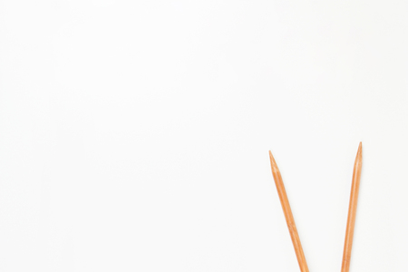 Wooden knitting needles frame with copy space for text on white backgroundの写真素材