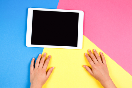 Kid hands with tablet computer on colorful background.の写真素材