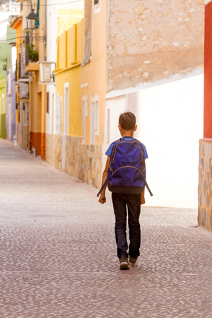 Back view of kid with backpack outdoors in european city.の写真素材