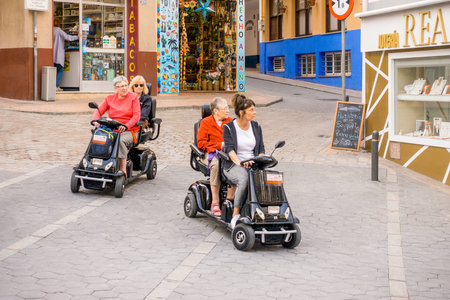 Benidorm, Spain - January 29, 2018: Womans using hired mobility scooters in the street of Benidorm, Spainのeditorial素材