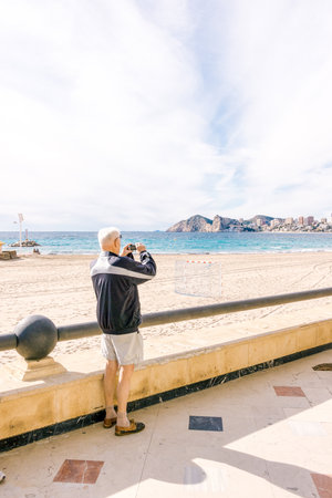 Benidorm, Spain - January 14, 2018: Elderly tourist taking photo of Benidorm, Spain.のeditorial素材