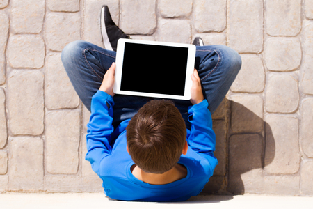 Child with tablet computer sitting outdoors. Top view.の写真素材