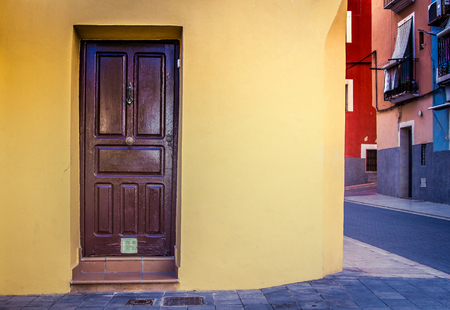 Brown door and yellow building facade in the streetの写真素材