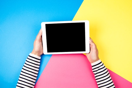 Womans hands with tablet computer on colorful background.