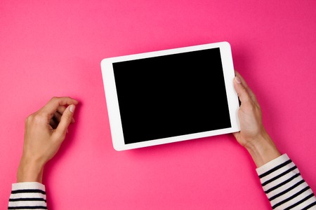 Womans hands with tablet computer on pink background.の写真素材