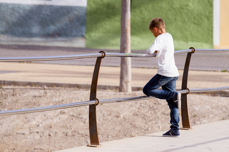 Kid boy standing alone on the bridge and looking down to the waterの写真素材