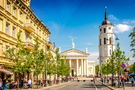 Vilnius, Lithuania - May 1, 2018: View to Vilnius city street -Gedimino avenue, Vilnius Cathedral and bell tower with people walking and riding bike in sunny day.のeditorial素材