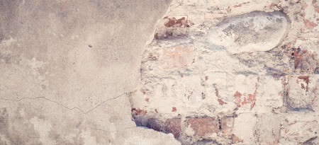 Old grungy brick wall with damaged plaster banner background texture.