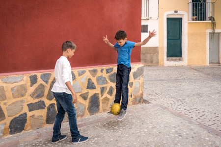 Boys playing with soccer ball outdoors in the streetの写真素材