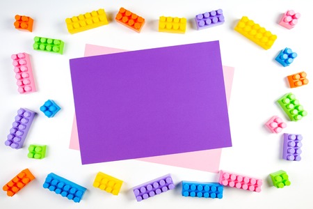 Colorful plastic construction blocks frame with violet blank card on white backgroundの写真素材
