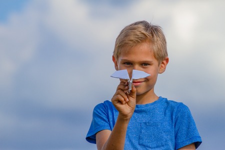 Boy throwing paper plane on summer day