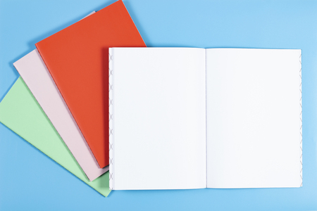 Open notebook and colorful notebooks on blue backgroundの写真素材