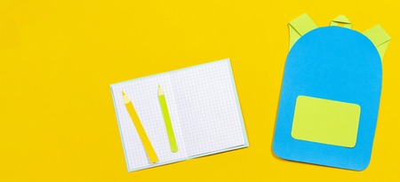 School bag backpack, notebooks and pencils paper cut on yellow backgroundの写真素材