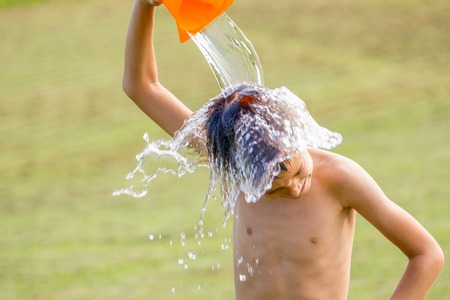 Little boy pouring cold water on his head outdoorsの写真素材