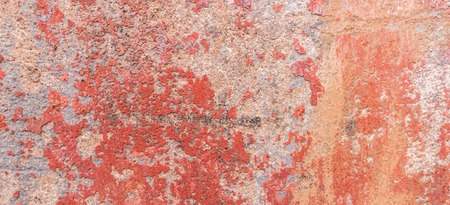 Old weathered painted wall background texture. Red dirty peeled plaster wall with falling off flakes of paint.の写真素材