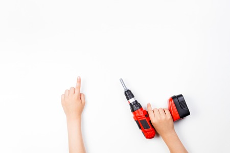 Childs hands on white background. Boy pointing finger up and holding toy drill.