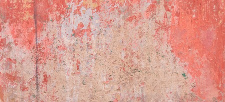 Old weathered painted wall background texture. Red dirty peeled plaster wall with falling off flakes of paint.の写真素材