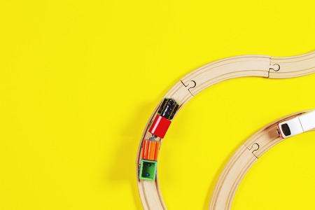 Toy trains and wooden rails on yellow and blue color backgroundの写真素材