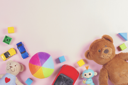 Baby kids toys frame with teddy bear, toy cars, colorful bricks on pink backgroundの写真素材