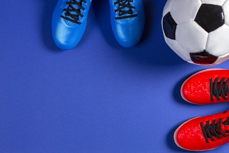 Soccer football background. Top view of soccer ball and two pair of soccer football sports shoes on blue backgroundの写真素材