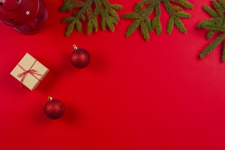 Christmas composition. Fir tree branches, christmas decorations and present gift box on red backgroundの写真素材