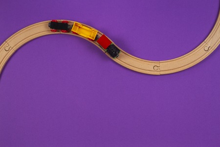 Toy train and wooden rails on purple violet backgroundの写真素材