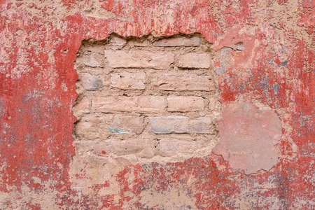 Old weathered peeled plaster brick wall background texture.