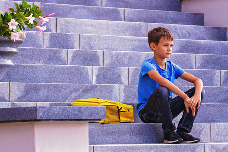 Boy with backpack sitting on the stairs outdoorsの写真素材