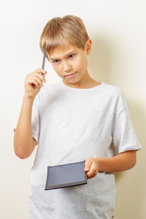 Kid thinking what to draw with graphic tablet and stylus pen
