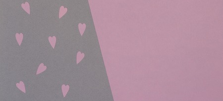 Small pink paper cut hearts on gray and pink background with copy spaceの写真素材