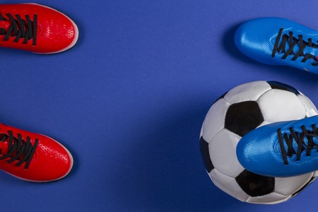 Top view of soccer ball and two pairs of soccer football sports shoes on blue backgroundの写真素材