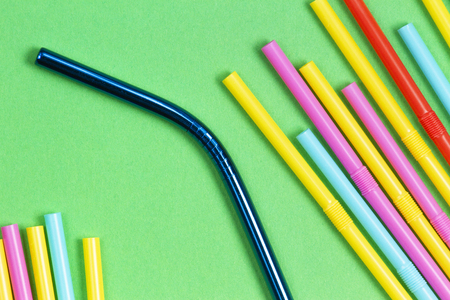 Stainless steel reusable drinking straw with plastic straws on green backgroundの写真素材