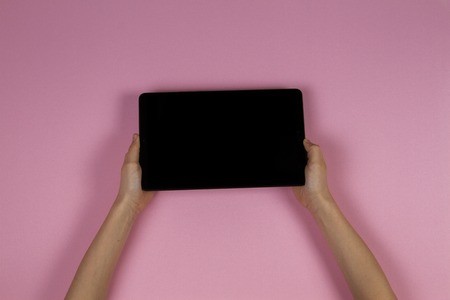 Kid hands with tablet computer on pink backgroundの写真素材