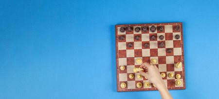 Kid hands over a chessboard playing chess game on blue background, top viewの写真素材