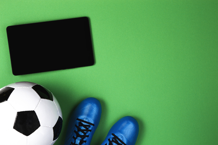 Soccer football background. Football boots, ball and tablet computer on green backgroundの写真素材