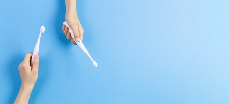 Kid hands with electric toothbrushes on blue backgroundの写真素材