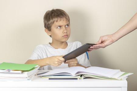 Video games addiction. Mother taking tablet away from the kid hands