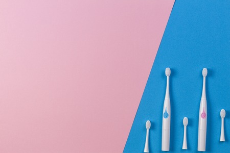 Two electric toothbrushes with three brush heads on blue and pink background. Top viewの写真素材