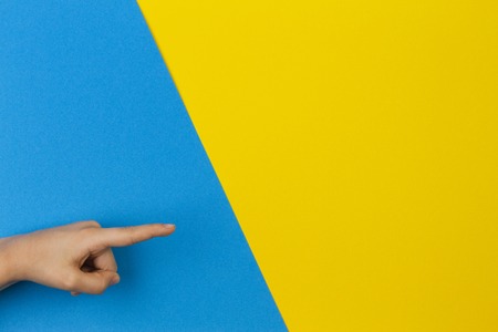 Kid hands pointing to something on blue and yellow backgroundの写真素材