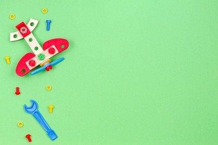 Toy wooden plane, bolts and toys tools on green backgroundの写真素材