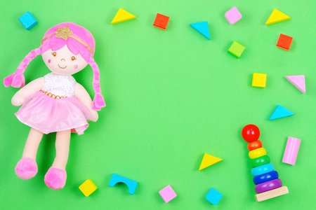 Kids toys background frame with toy doll and colorful blocks on green backgroundの写真素材