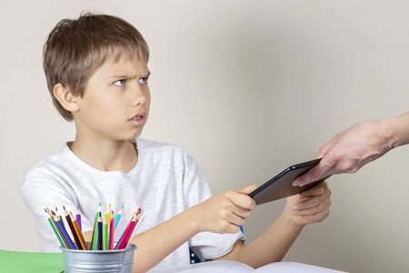 Video games addiction. Mother taking tablet away from the kid handsの写真素材
