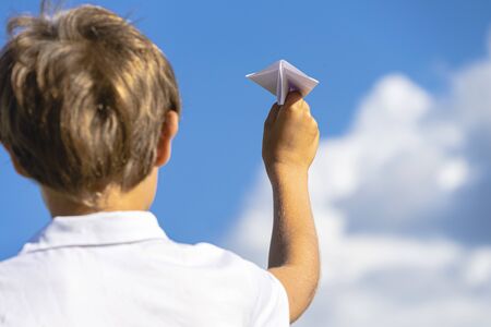 Kid hand with white paper plane against blue skyの写真素材