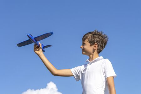 Boy playing with blue toy plane against blue skyの写真素材